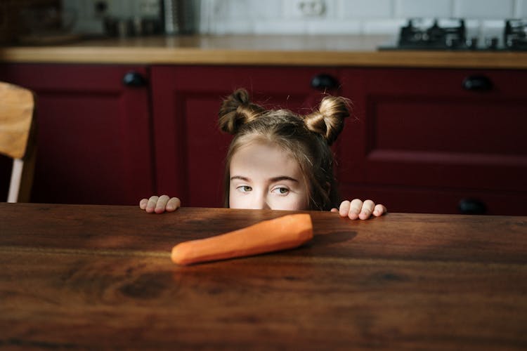 Girl Peeking Over Brown Wooden Table