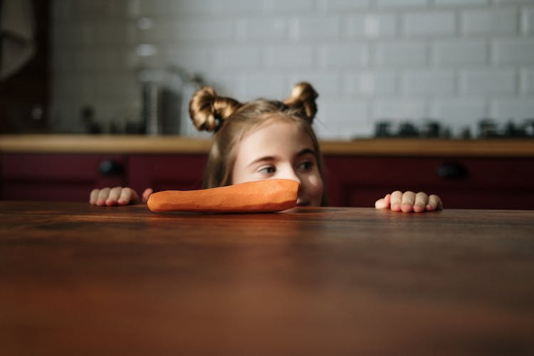 Girl Peeking Over Brown Wooden Table