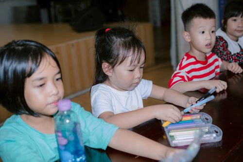 Free Group of children drawing together in a classroom, using colorful markers and enjoying creative play. Stock Photo