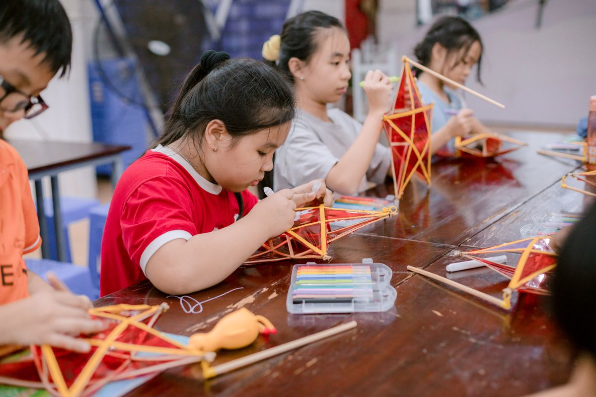 Children crafting traditional geometric paper lanterns together in a classroom