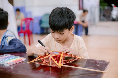 Free A young boy focused on decorating a traditional craft indoors. Creative and cultural activity. Stock Photo