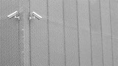 两个监控摄像头安装在纹理金属墙上，展示着现代建筑风格