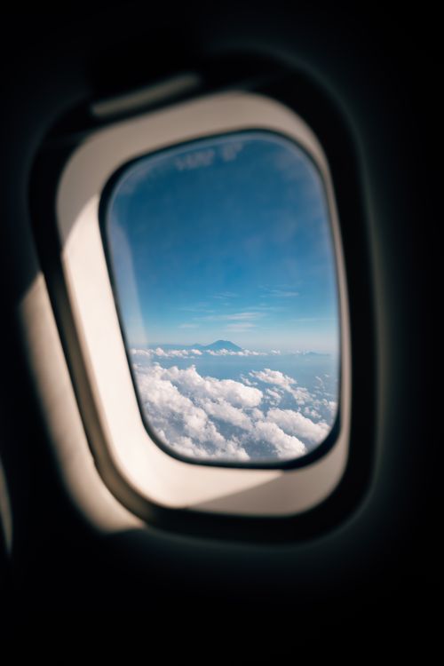 Free Spectacular view of a mountain peak above the clouds from an airplane window. Stock Photo