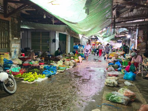 Free A vibrant indoor market bustling with people and colorful produce stalls on a wet day. Stock Photo