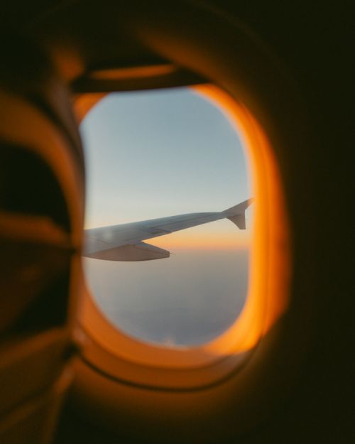 Free A serene view of an airplane wing through the window at sunset, capturing the sky's gradient. Stock Photo