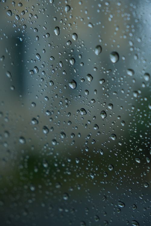 Free Close-up of raindrops on a window with a blurred background creating an abstract texture. Stock Photo