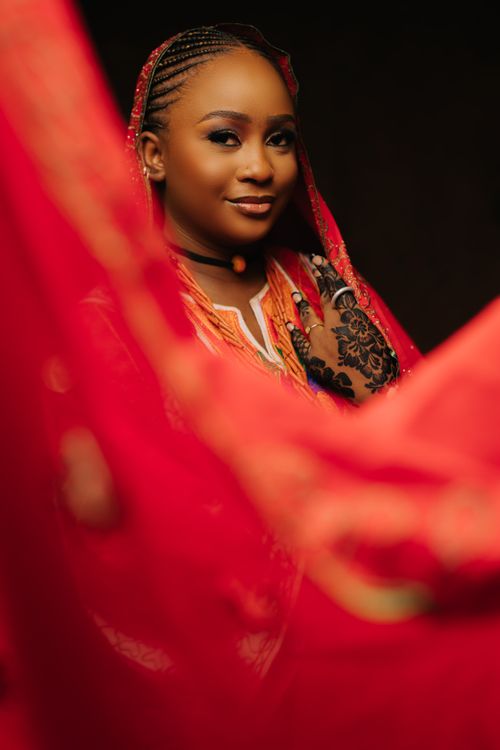 Free Beautiful portrait of a woman in a traditional red garment with a warm and inviting expression. Stock Photo