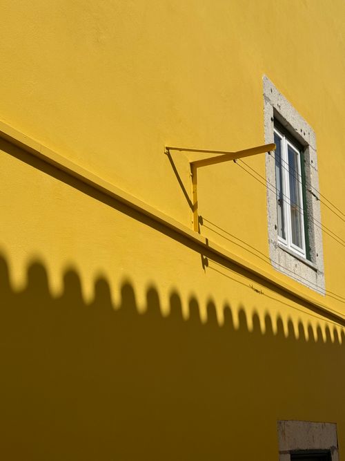 Free Bright yellow wall with a shadow and a window in Cascais, Lisbon, Portugal. Stock Photo