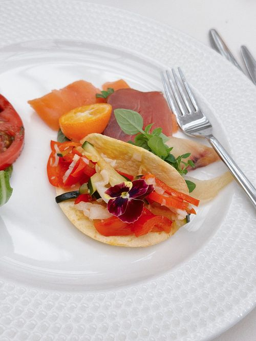 Free A gourmet dish featuring smoked salmon, fresh fruits, and edible flower garnish on a stylish white plate. Stock Photo