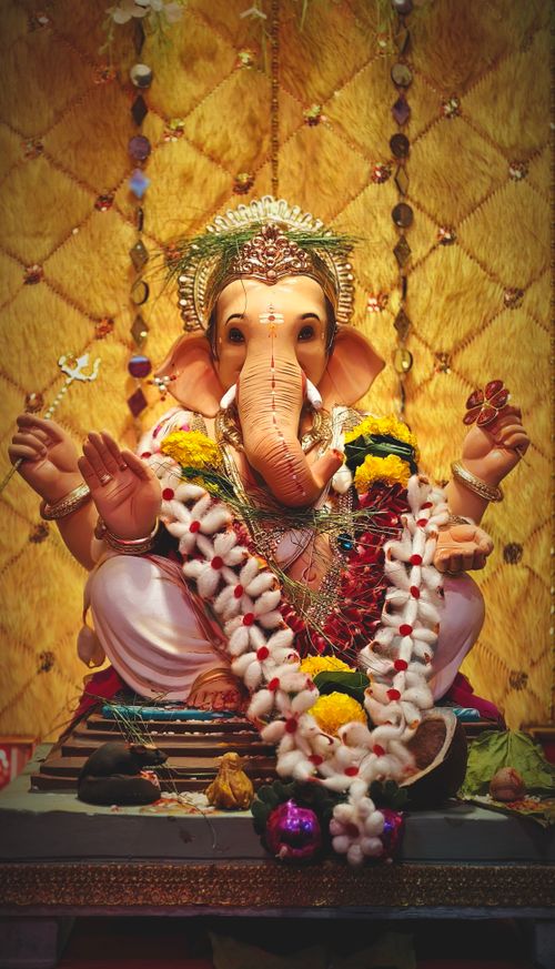 Free Detailed close-up of a decorative Lord Ganesha statue adorned with flowers and jewelry. Stock Photo