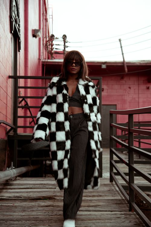 Free Stylish woman walking on industrial walkway in a black and white coat. Stock Photo