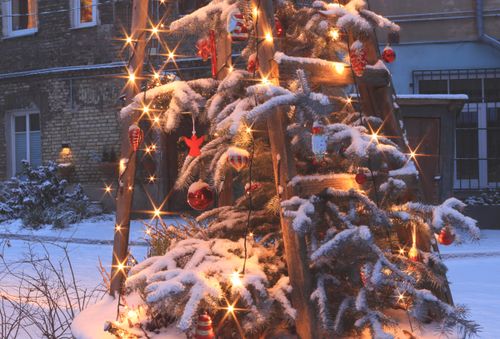Free Snow-covered Christmas tree adorned with lights and ornaments in a wintery outdoor setting. Stock Photo