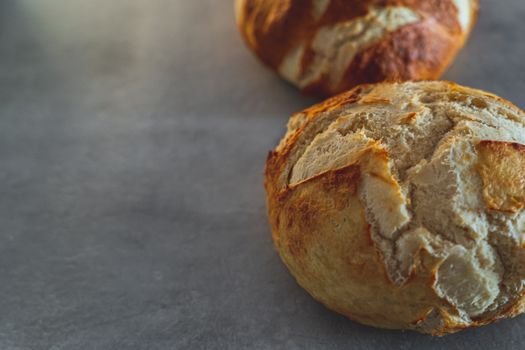 Close-up of freshly baked crusty breads on a rustic table surface, showcasing texture and craftsmanship.