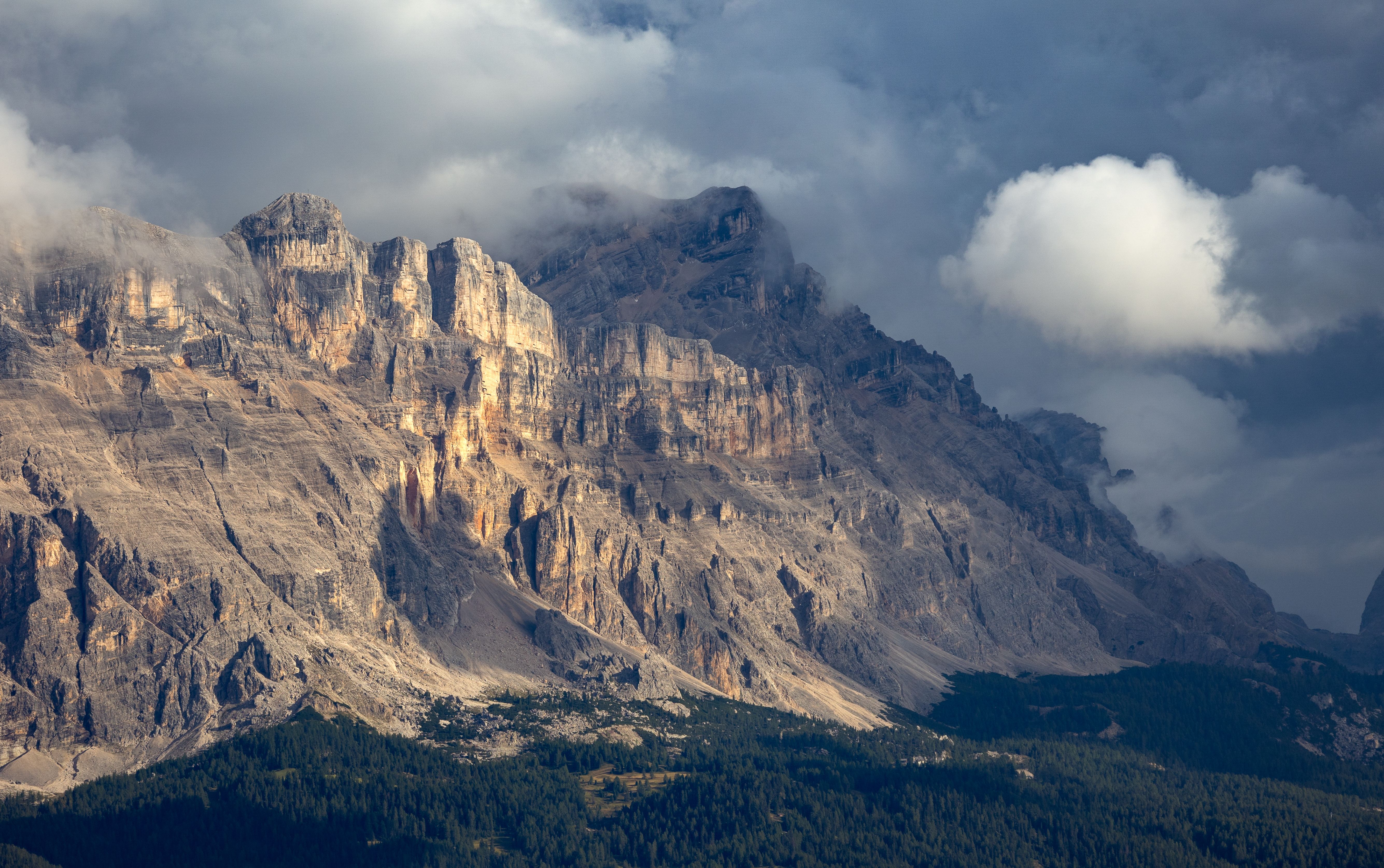 Stunning view of the Dolomites with dramatic clouds and lighting during sunset, capturing the beauty of nature.