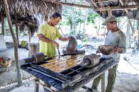 Man Pouring Hot Sugar Cane on Wooden Molds