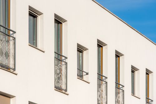 Free Modern building facade with symmetrical windows and metal grilles under a clear blue sky. Stock Photo