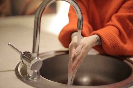 Hands rinsing a silicone seal under running water at a sink