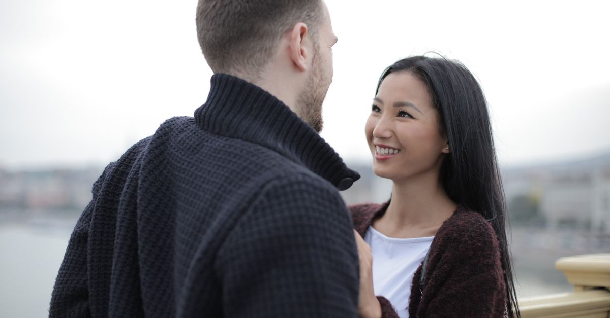 A happy couple smiling and enjoying a romantic moment together outdoors during the day.
