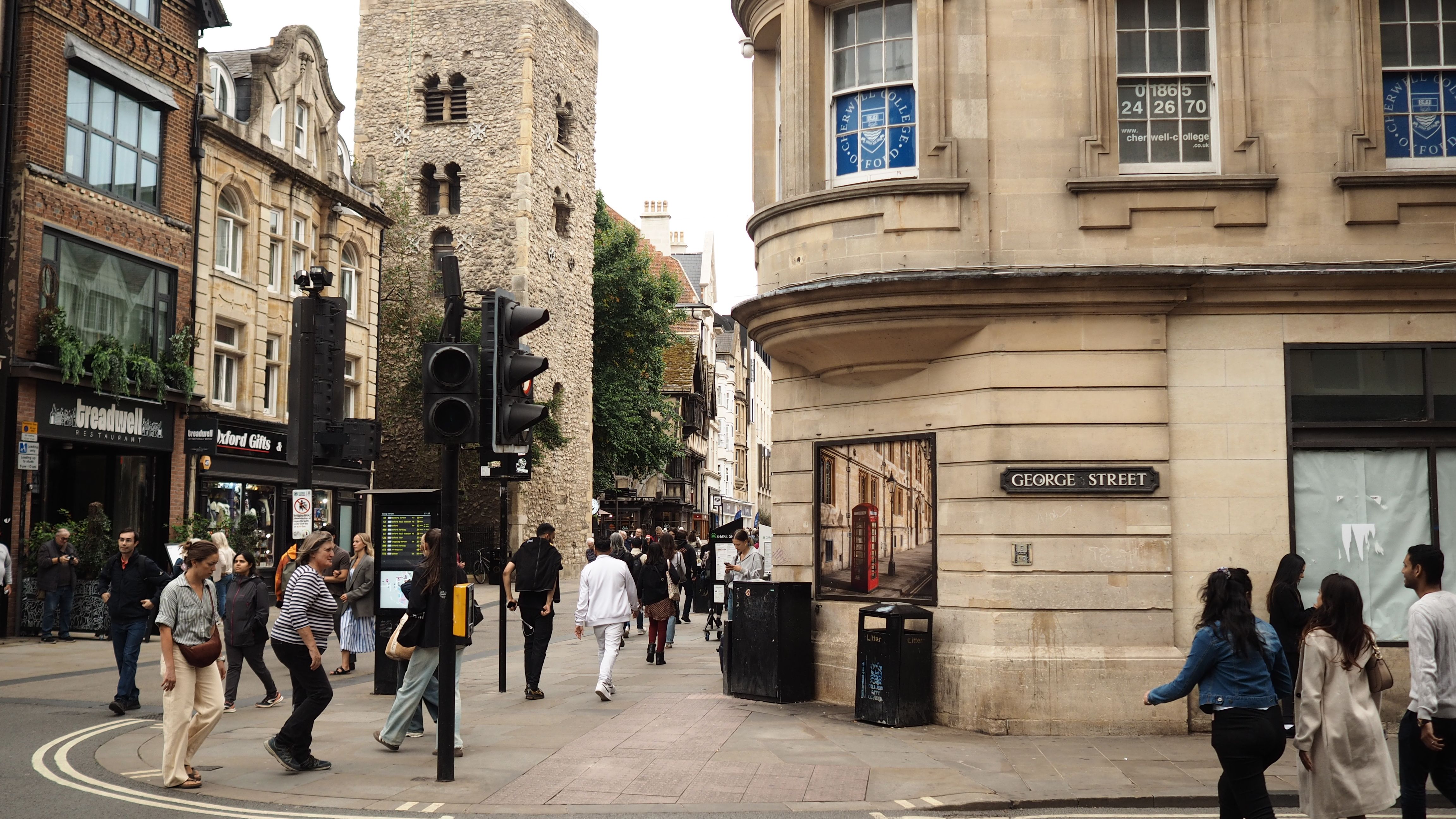 Street view of George Street in Oxford with historic buildings and people walking.
