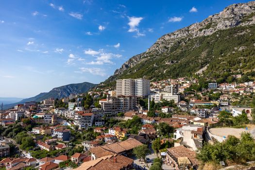 Picturesque view of Krujë city nestled against mountains in Albania under a clear blue sky.