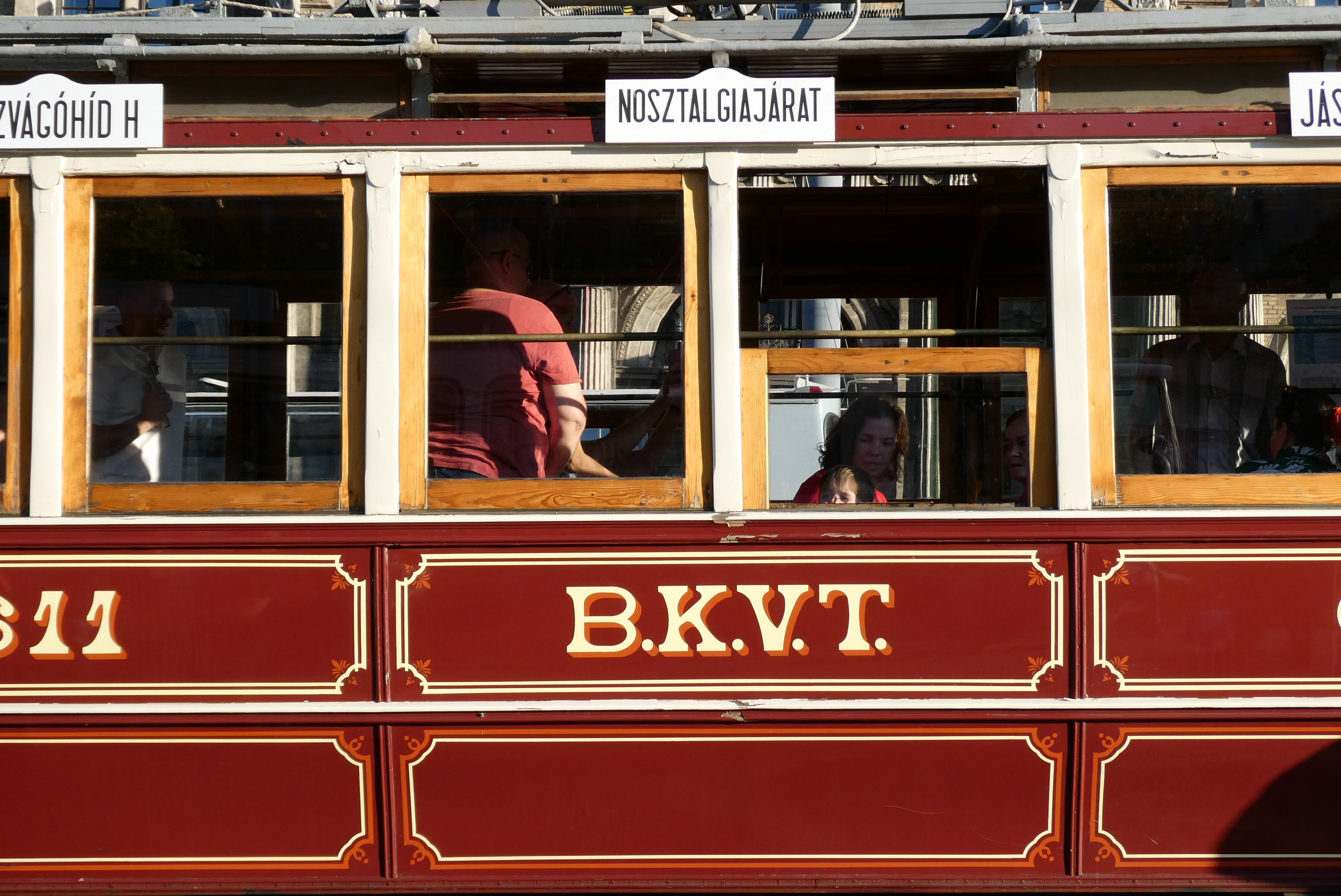 Classic Budapest tram with passengers seen through windows on a sunny day.