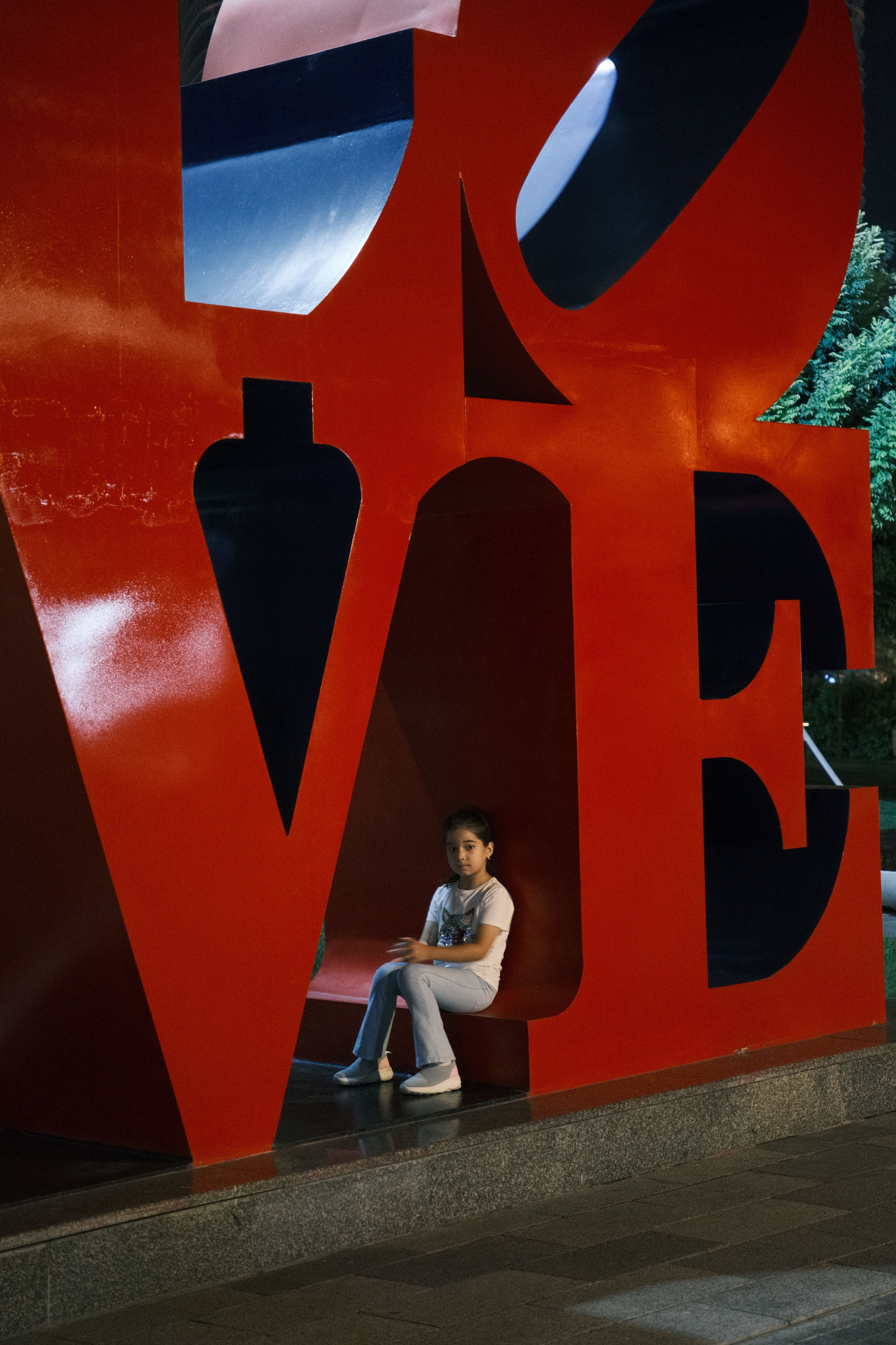 A child sits at the iconic LOVE sculpture in Tashkent during night.