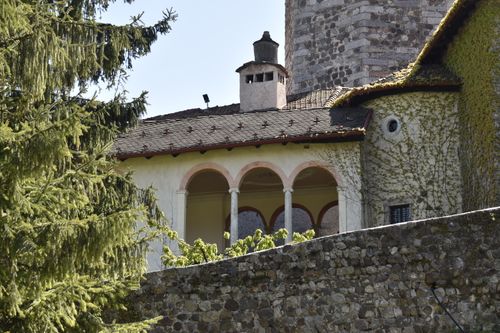 Free Picturesque view of a historic building with stone walls and arched veranda, surrounded by lush greenery. Stock Photo