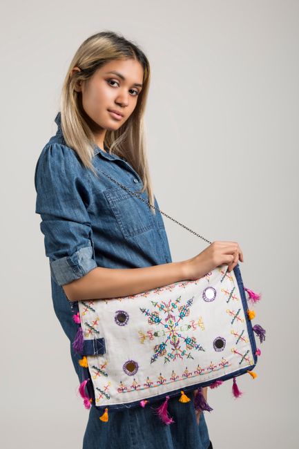 Young woman posing in denim with a colorful embroidered bag on a white background. - Expert Tips for Selecting the Right Handbag