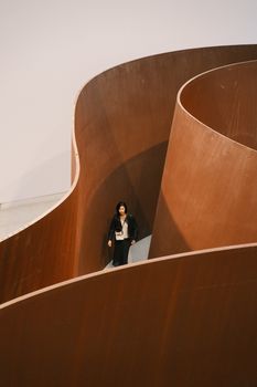 A person walks within an abstract spiral sculpture in a modern setting.