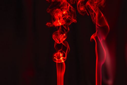 Free Artistic red smoke swirling on a dark backdrop creating an ethereal effect. Stock Photo