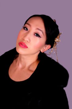 Close-up portrait of an elegant woman with artistic makeup and hair accessories.