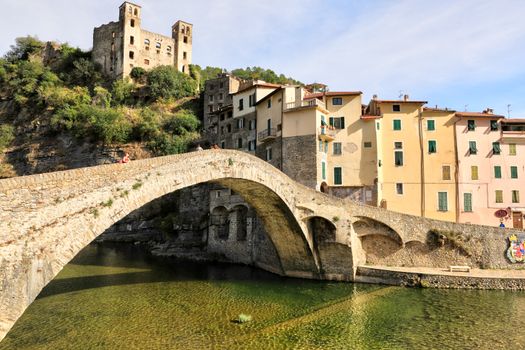 A scenic view of Dolceacqua's ancient stone bridge and castle under a clear summer sky.