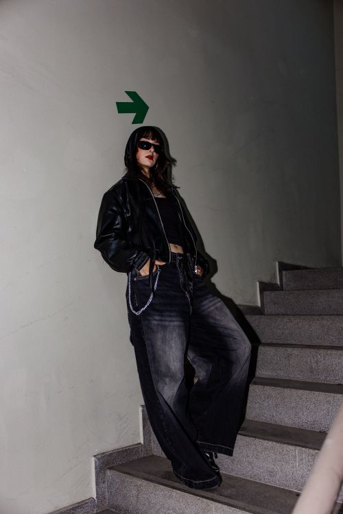 Free Stylish model in dark clothing poses on a staircase with an urban vibe. Stock Photo