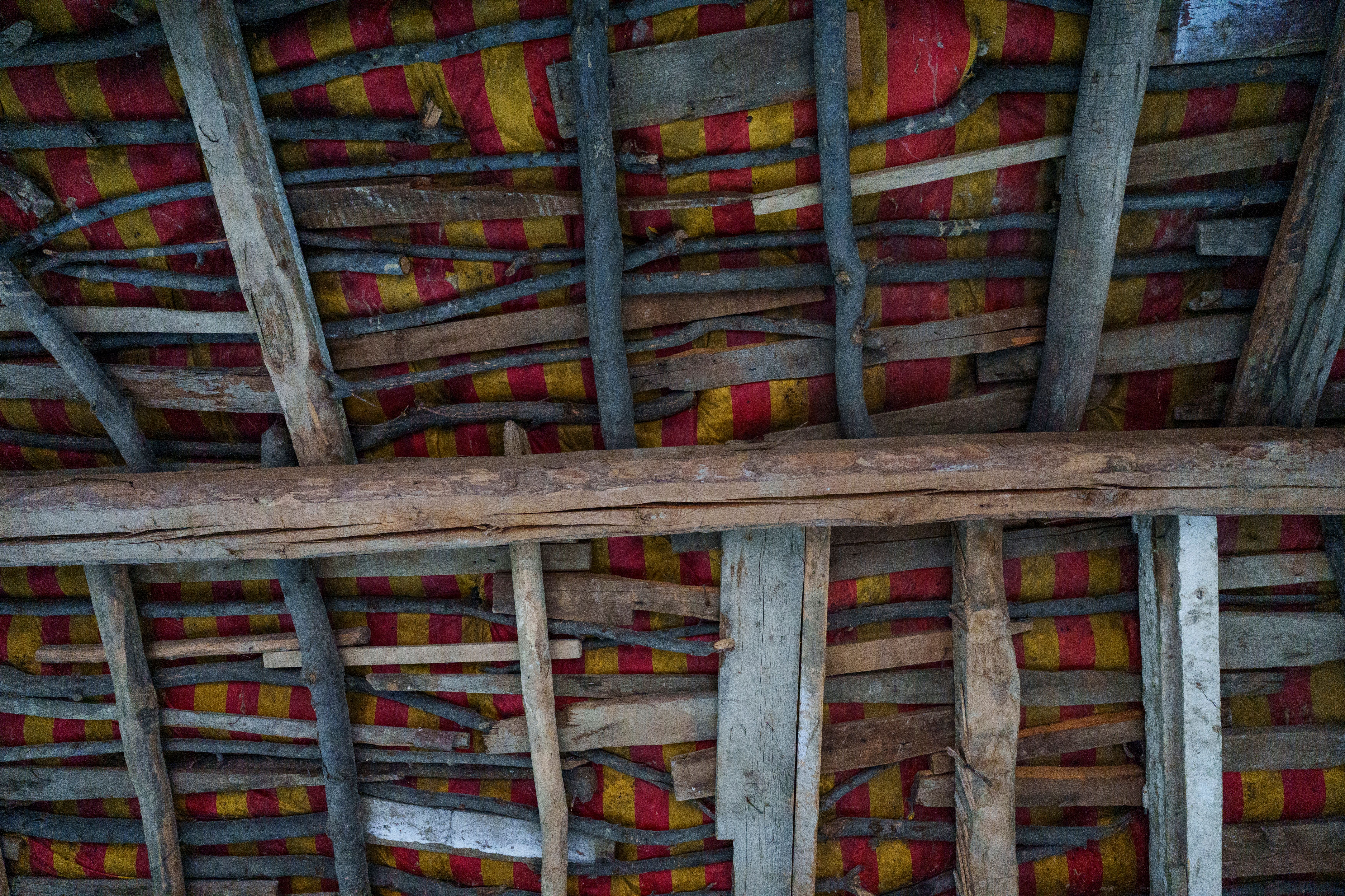 Detail view of a rustic wooden roof structure with colorful insulation panels in Samarkand, Uzbekistan.