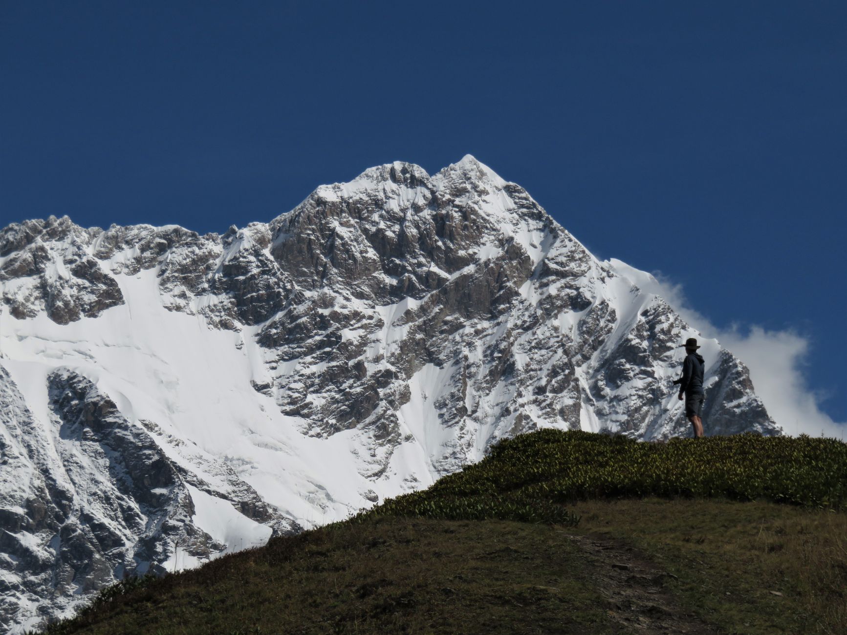 A lone hiker admires the breathtaking snowy peaks of the Caucasus Mountains in Adishi, Georgia.