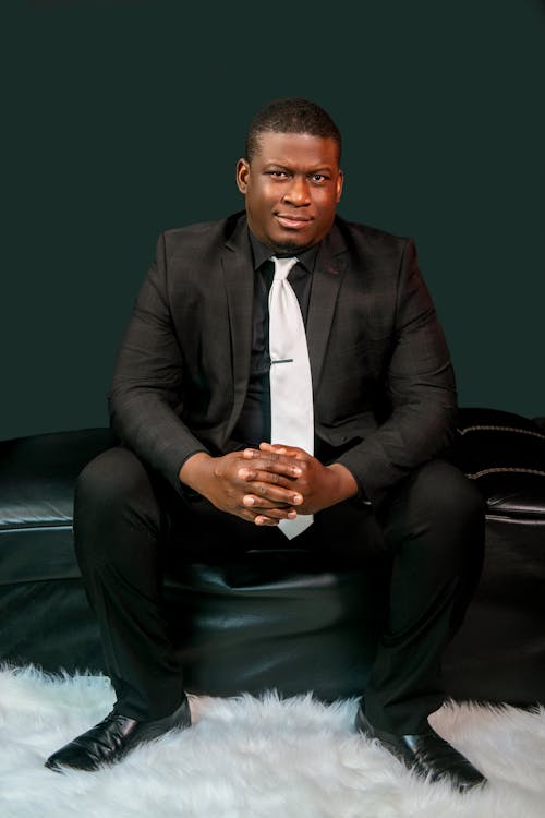 Man In Black Suit Sitting On Leather Couch