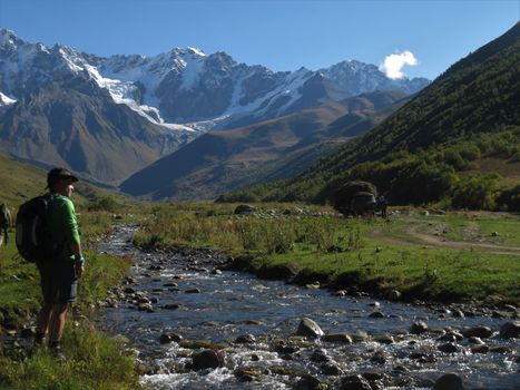 A hiker exploring the scenic Ushguli Valley in Georgia's Caucasus Mountains, surrounded by natural beauty.