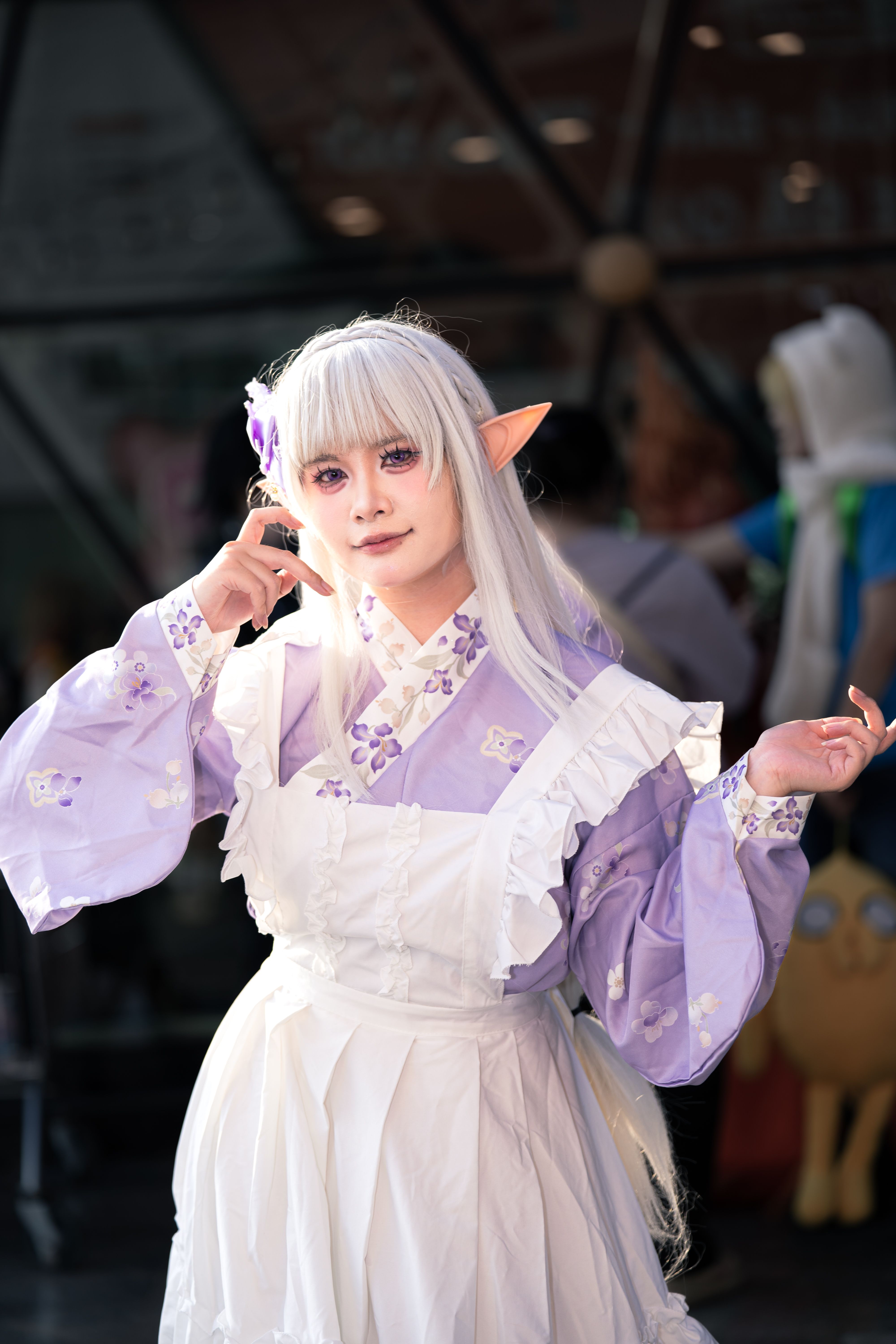 Elf cosplayer in a lavender kimono poses at a convention. Fantasy and cosplay theme.