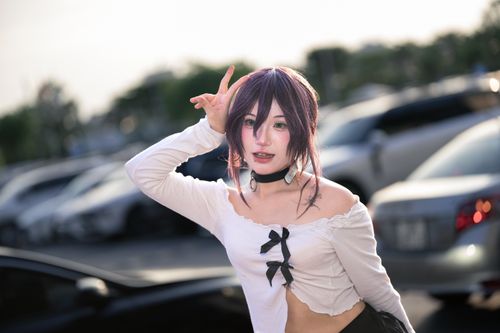 Free A young adult cosplayer in anime attire poses energetically in a sunlit parking lot. Stock Photo