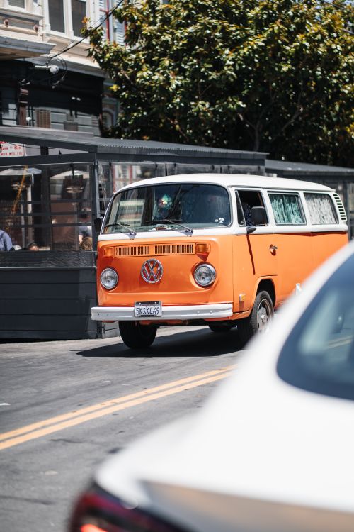 Free Vintage orange Volkswagen van driving on a sunny day in San Francisco. Stock Photo