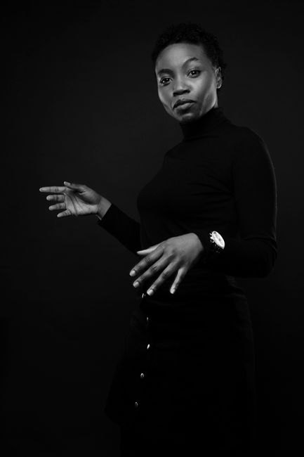 Striking black and white portrait of a stylish woman posing in a studio setting.