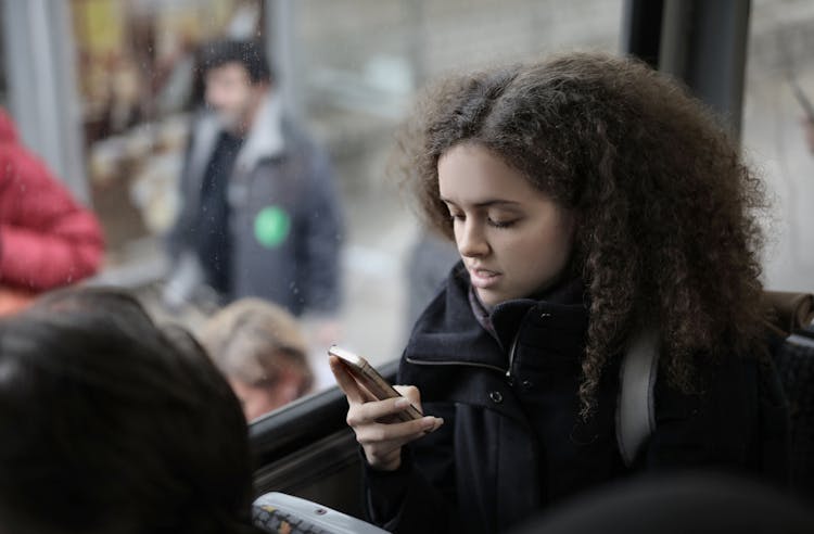 Thoughtful Young Lady Using Smartphone While Riding Bus