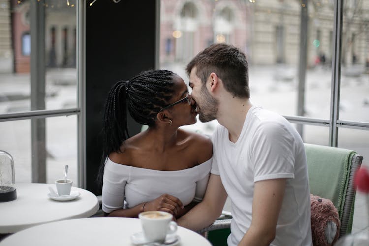 Happy Young Multiethnic Couple Kissing In Modern Cafe