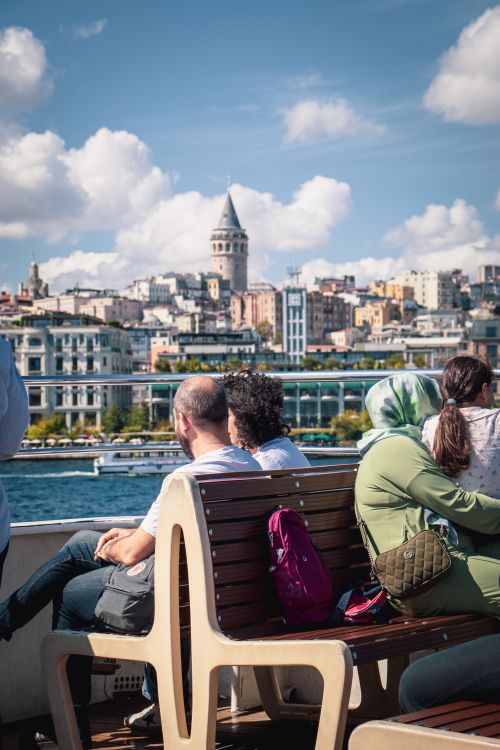 Free Passengers enjoy a ferry ride with a view of Istanbul's iconic Galata Tower. Stock Photo