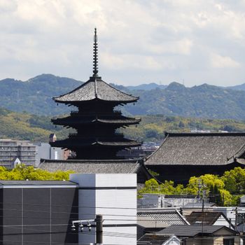 A stunning view of a traditional pagoda tower amidst modern Kyoto, Japan.（イメージ）