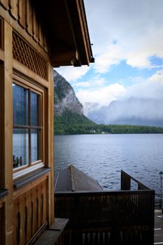 A tranquil alpine lake view with a wooden cabin and misty mountains in the background.