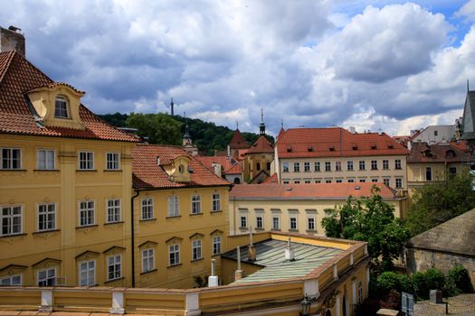 Charming view of Prague's historical buildings with red rooftops and cloudy sky.