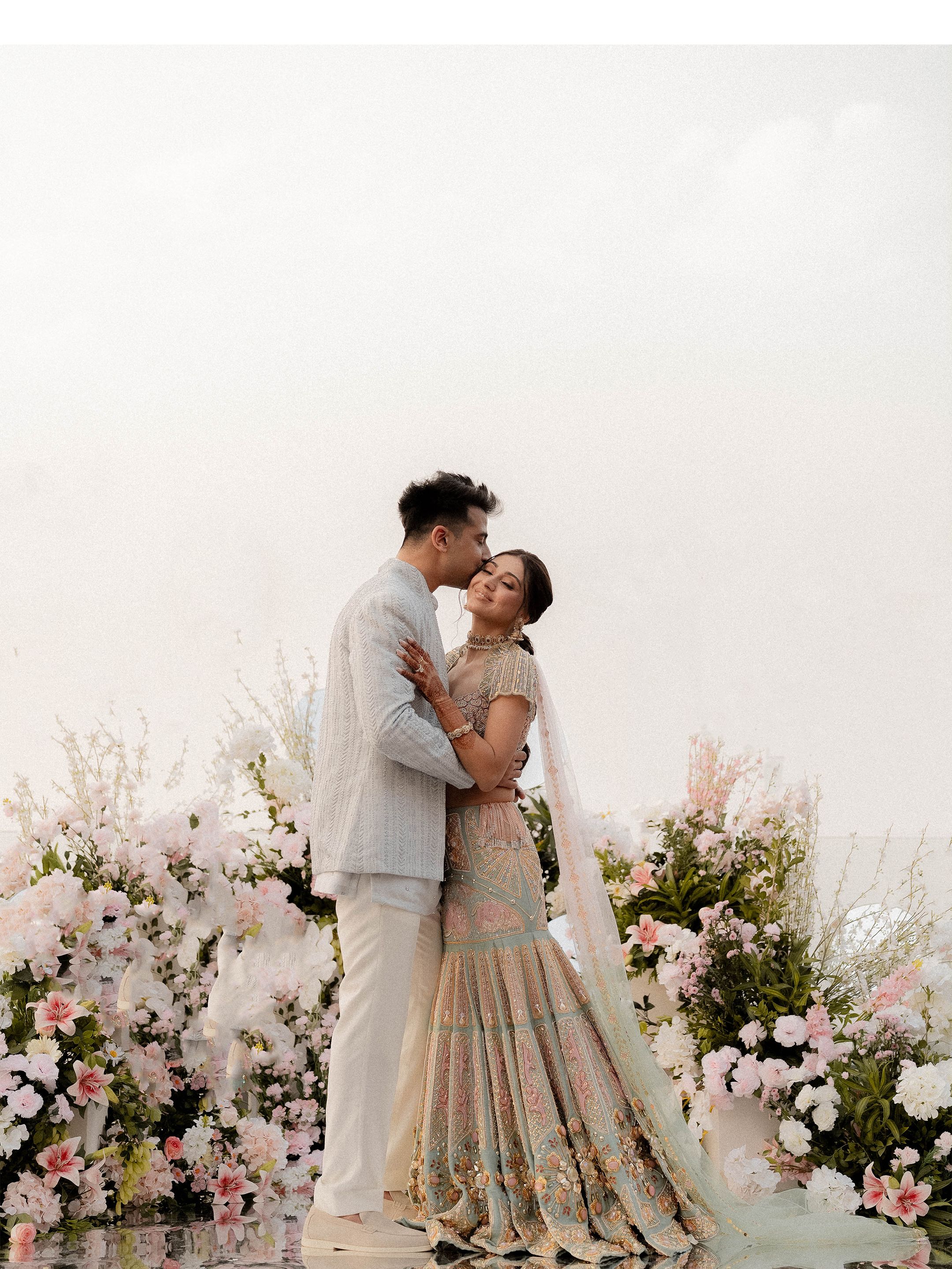 Couple embracing in a romantic outdoor wedding setting with floral decor.