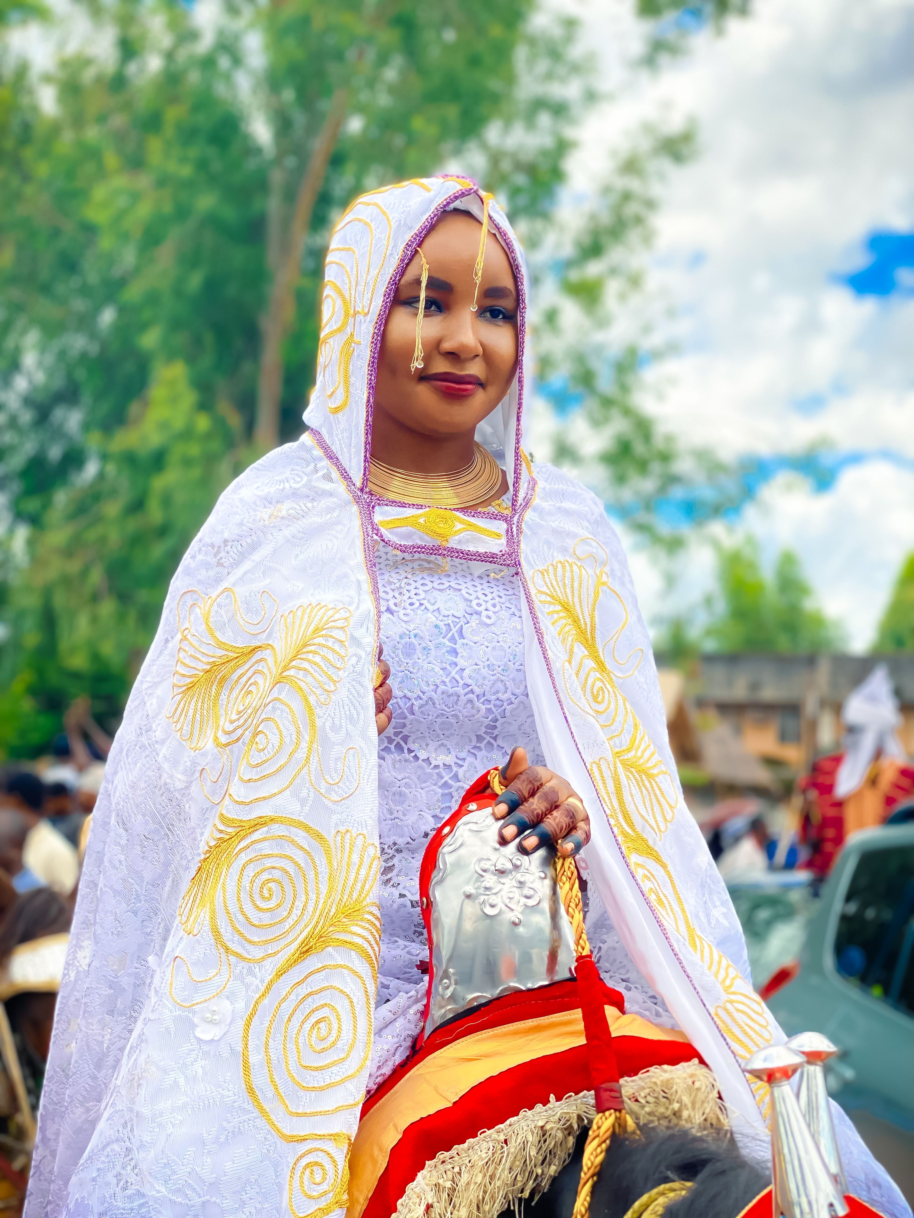 A Nigerian woman in traditional bridal attire participates in an outdoor cultural event in Kaduna.