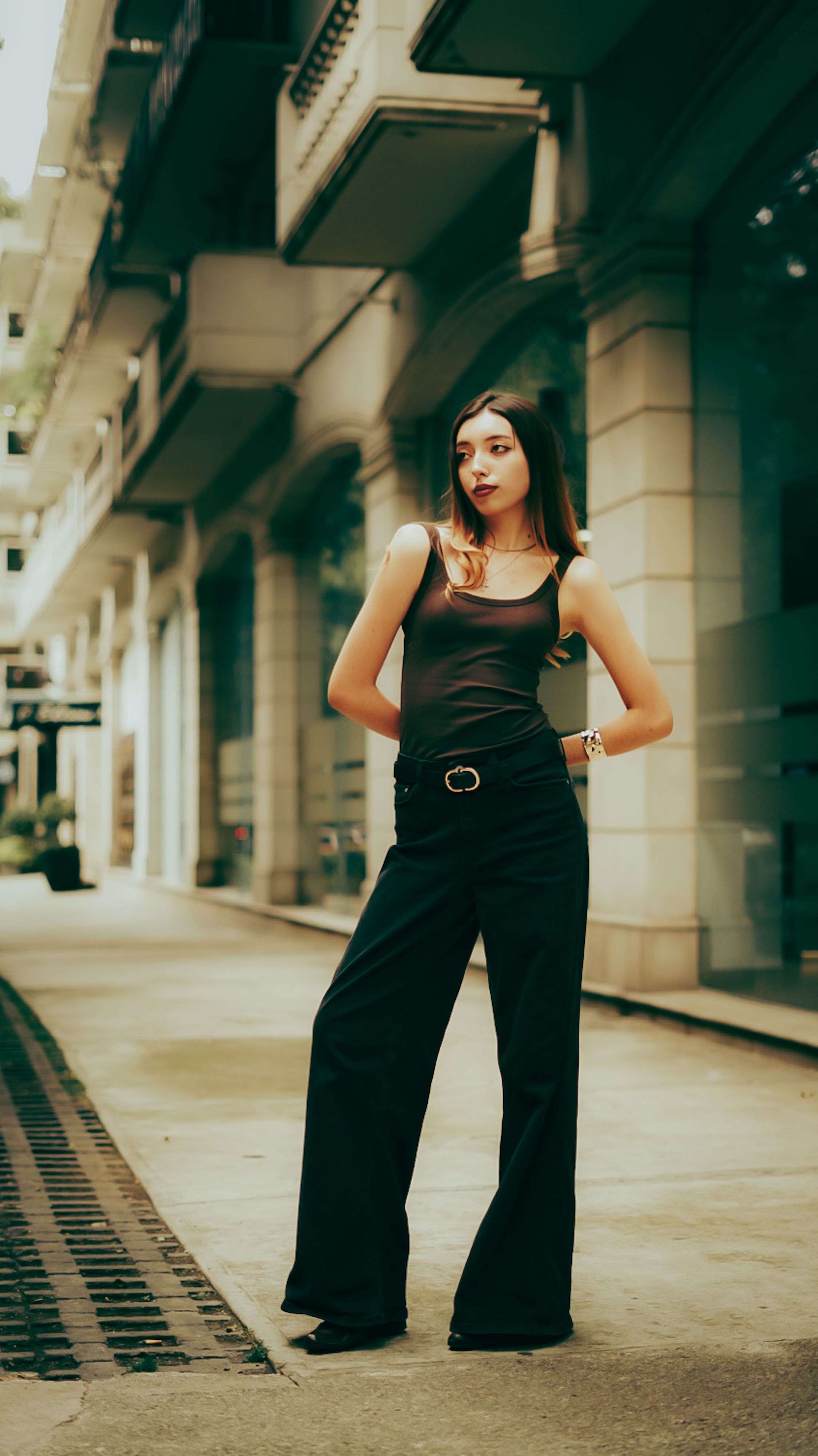 Elegant woman in a stylish outfit poses confidently on a bustling city street.